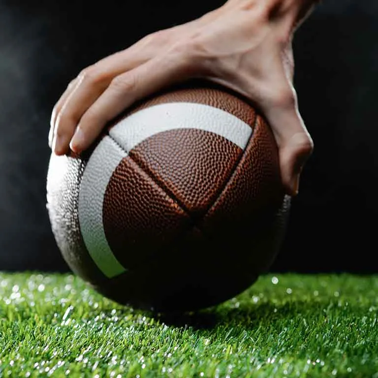 Mano tomando balon de futbol americano